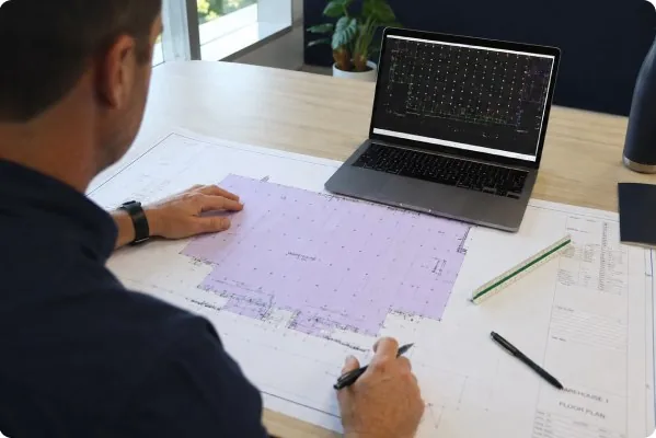 Reviewing emergency lighting floor plans beside a laptop
